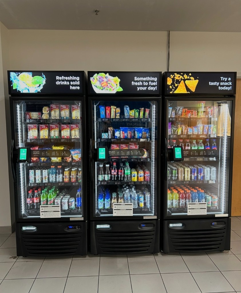 Three stocked smart cooler cabinets with glass doors and cashless payment screens